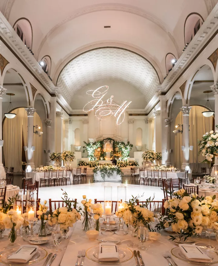 Glamorous wedding reception with a classic, white-and-greenery motif with candles at Vibiana in Los Angeles.