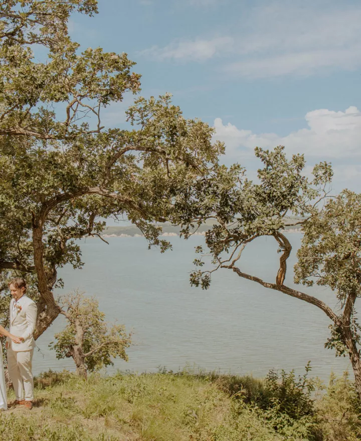 Bride and groom share an embrace lakeside