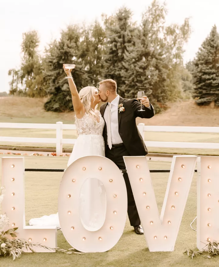 Kristin and Mason Share a Celebratory Kiss Behind a Lettered LOVE Sign