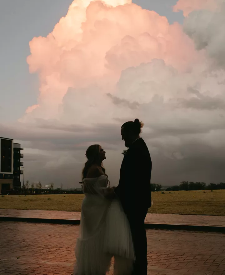 bride and groom backlit by stormy clouded sunset