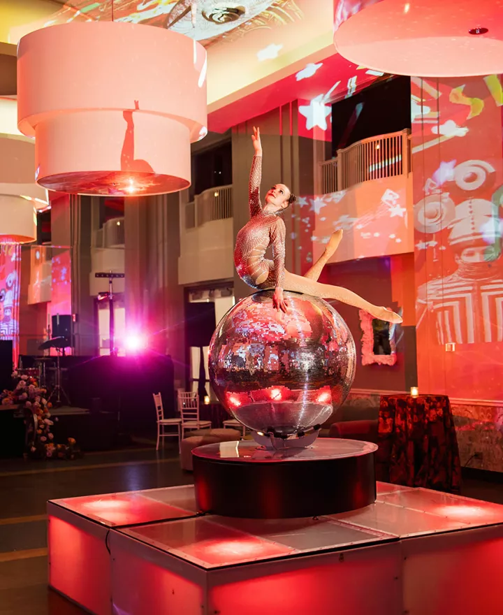 Entertainer balances on disco ball in lively, colorful reception at The Beach Club