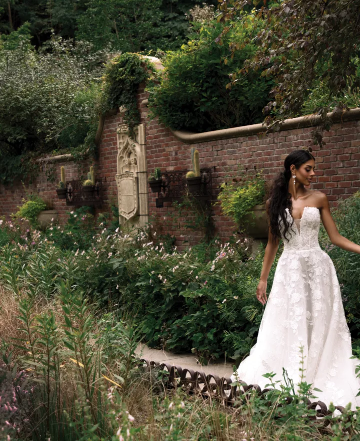Model Kami Buchanan poses in a strapless lace gown against the verdant backdrop of the Lauritzen Gardens