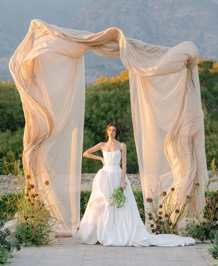 Model poses under architectural and organic altar against mountainous landscape at Topa Vista