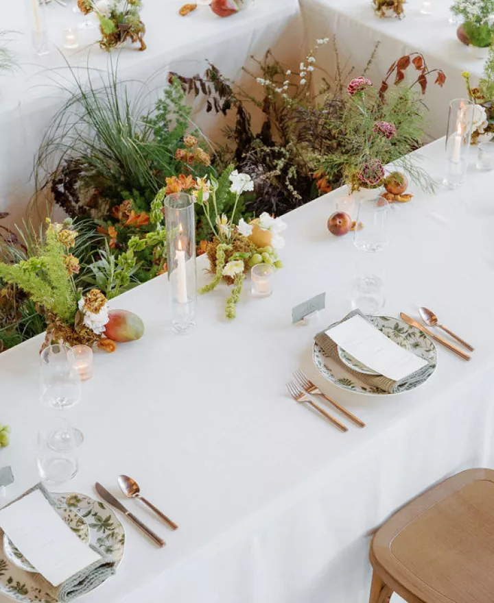 Organic florals in the middle of a rectangular table featuring simple, elegant design in glass house reception space at Woods & Co