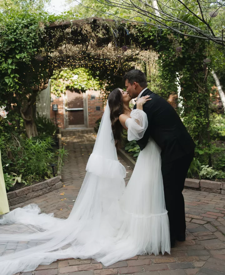 Bride and groom share a kiss after exchanging vows under an ivy trellis at The Bohemian Gardens