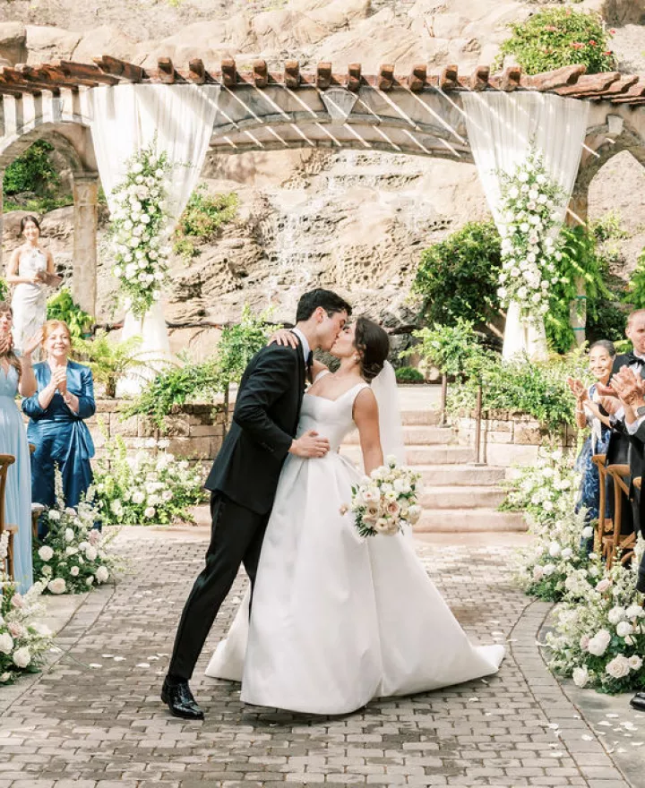 Bride and groom share a kiss at the end of the aisle after exchanging vows in outdoor ceremony at Villa Loriana