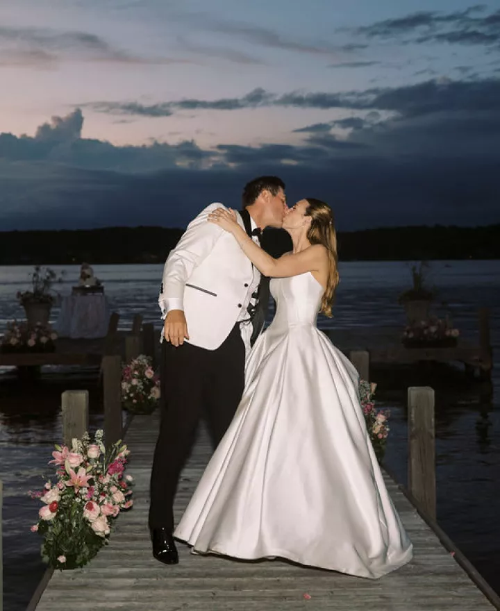 Bride and groom share a kiss against the sunset on Pewaukee Lake