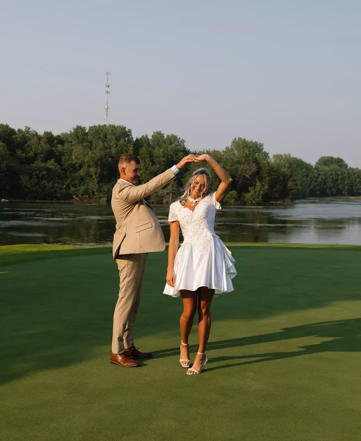 Groom twirls bride on golf course at rehearsal dinner