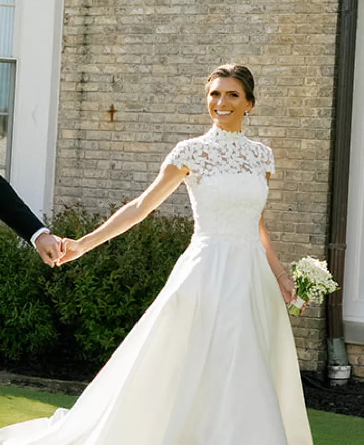 Bride and groom hold hands while walking the grounds of the Milwaukee Country Club