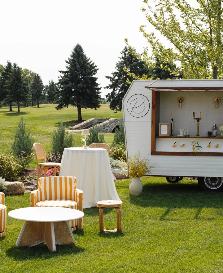 Sunny outdoor happy hour scene with yellow striped furniture and mobile bar at the Wexford at Emerald Greens