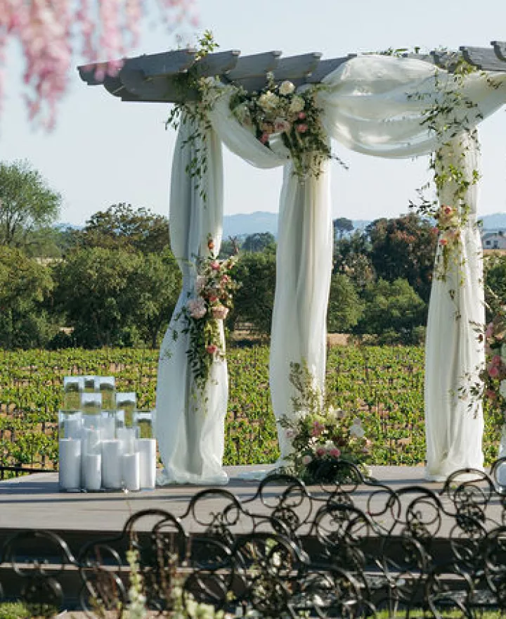 Styled ceremony scene featuring pink florals and white draping against the rolling hills of Mira Vista Estate