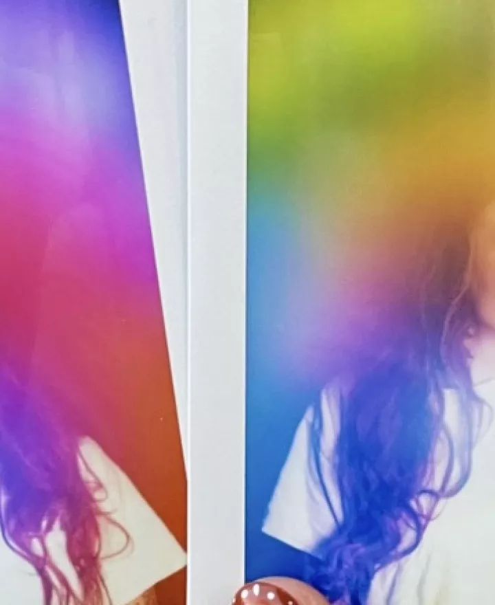 Two physical aura photograph polaroids by Vivid violet Aura side by side against a brick wall