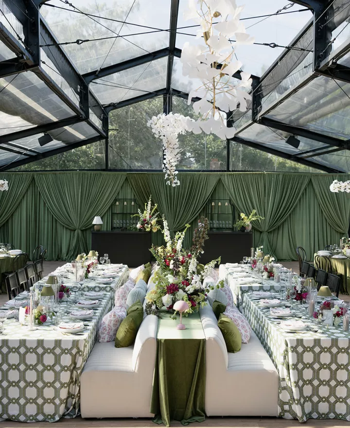 Bold maximalist reception design featuring luxe green draping and textured chandeliers at Woodland Glasshaus