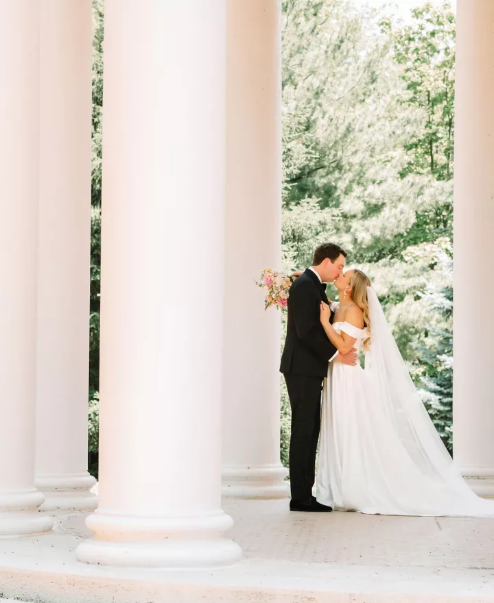 Bride and groom embrace in stone gazebo in wedding day at Arbor Day Farm