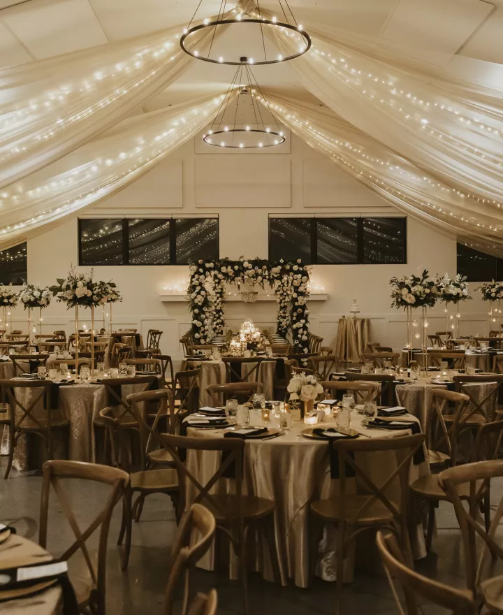 Classic and elegant reception design featuring draping and ivory florals in winter wedding at Woodhaven