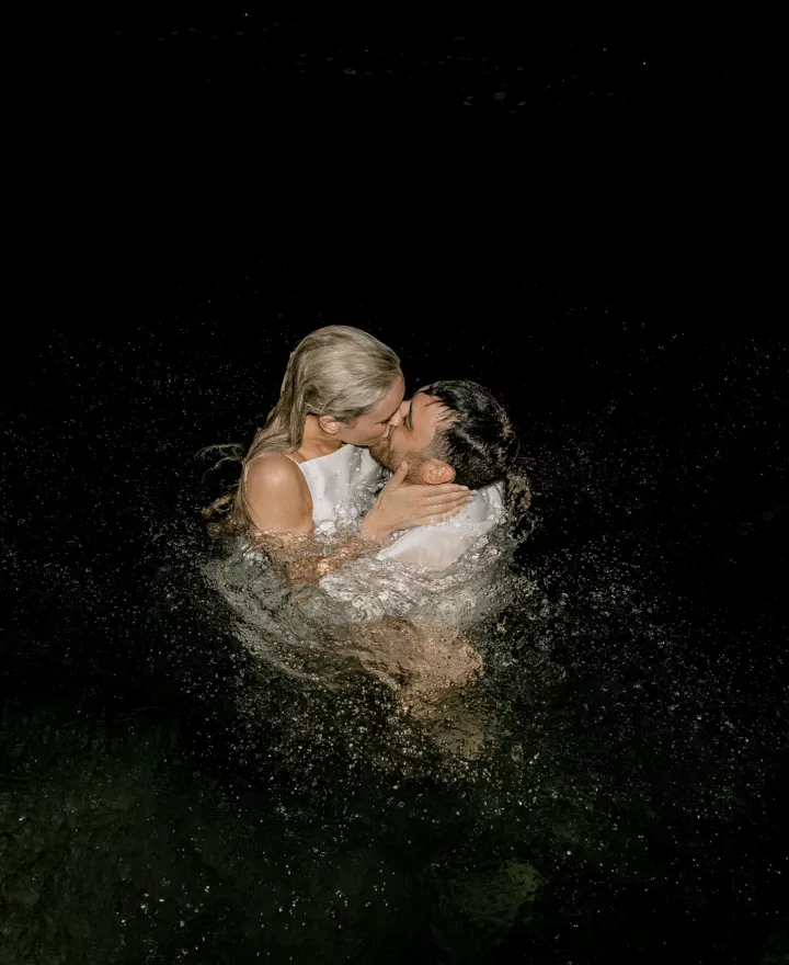 Bride and groom share a kiss in the waters of Lake Geneva in a light night dip in their wedding attire