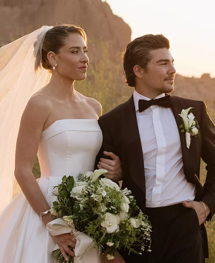 Bride and groom pose on the rocks of Camelback Mountain with the golden hour casting a glow behind them