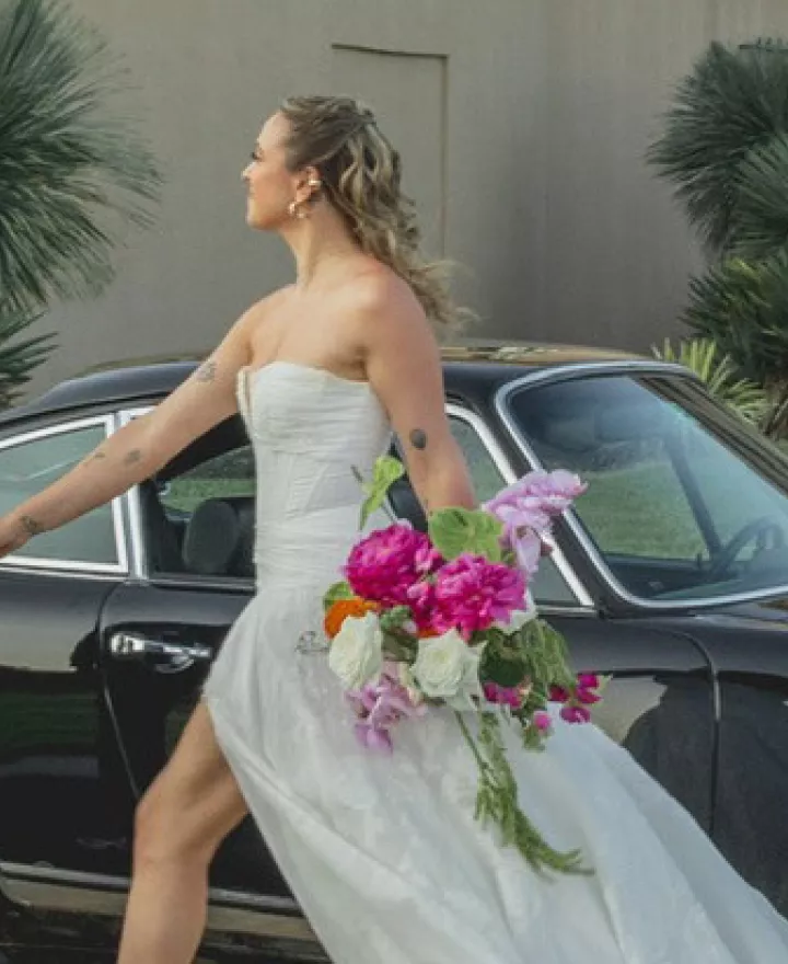 Groom leads bride across grounds of Maryhil Museum, a vintage car in the background
