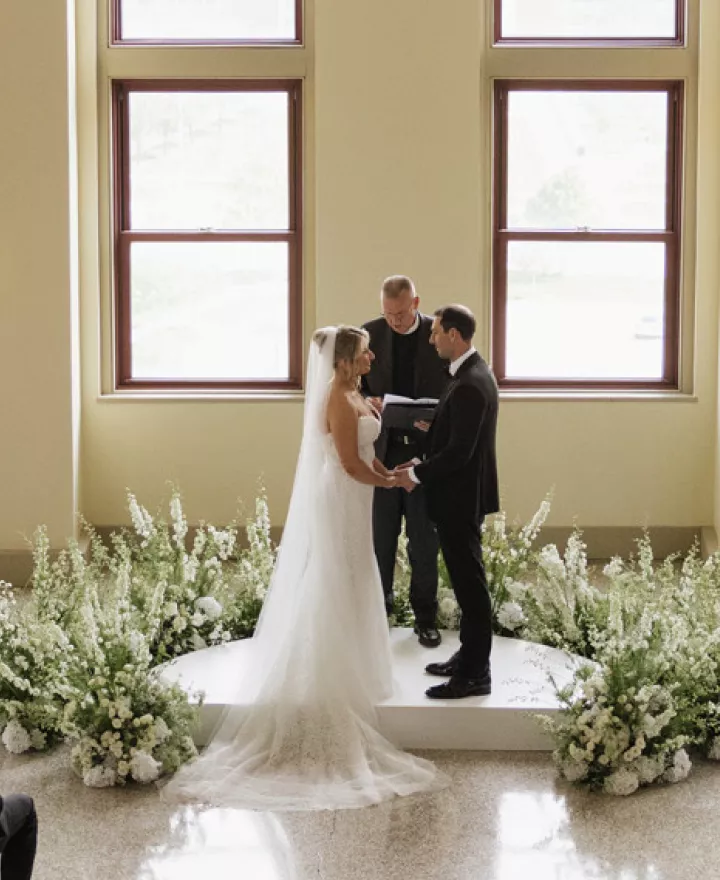 Bride and groom standing at the altar against a backdrop of floor-to-ceiling windows at Lumber Exchange Ballrooms