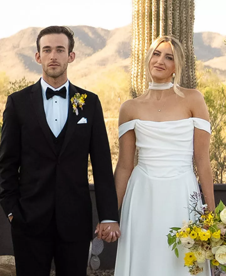 Bride and groom stand hand in hand at the altar, framed by bright blooms and cacti at The Willow Weddings & Event Center
