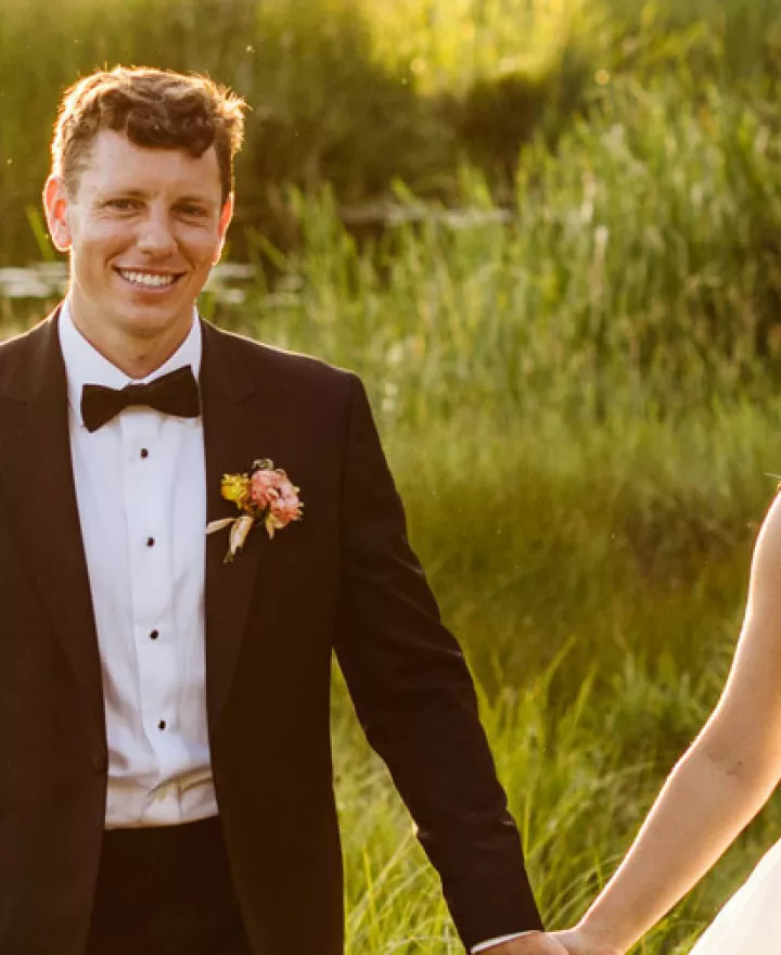 Bride and groom walk hand in hand in the golden hour light on the grounds of Sunriver Resort