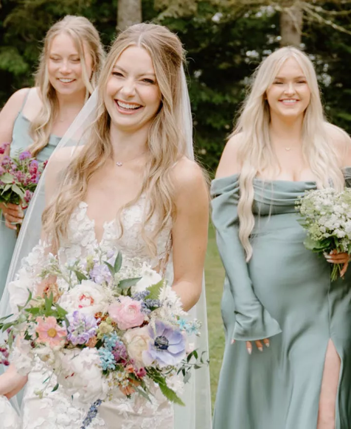 Bride walking the grounds of Woodland Meadow Farms alongside her sage-clad bridesmaids 