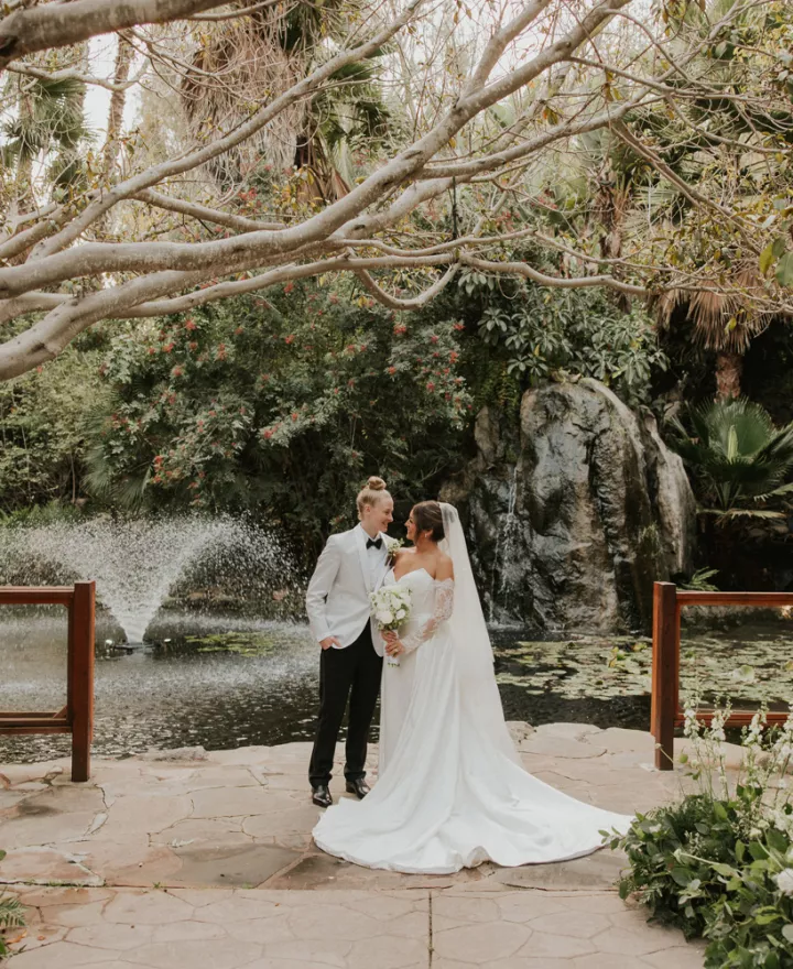 Taylor and Summer embrace on the grounds of Botanica on their wedding day