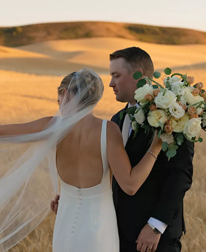 Abbey and Peter pose in golden fields of wheat on their wedding day