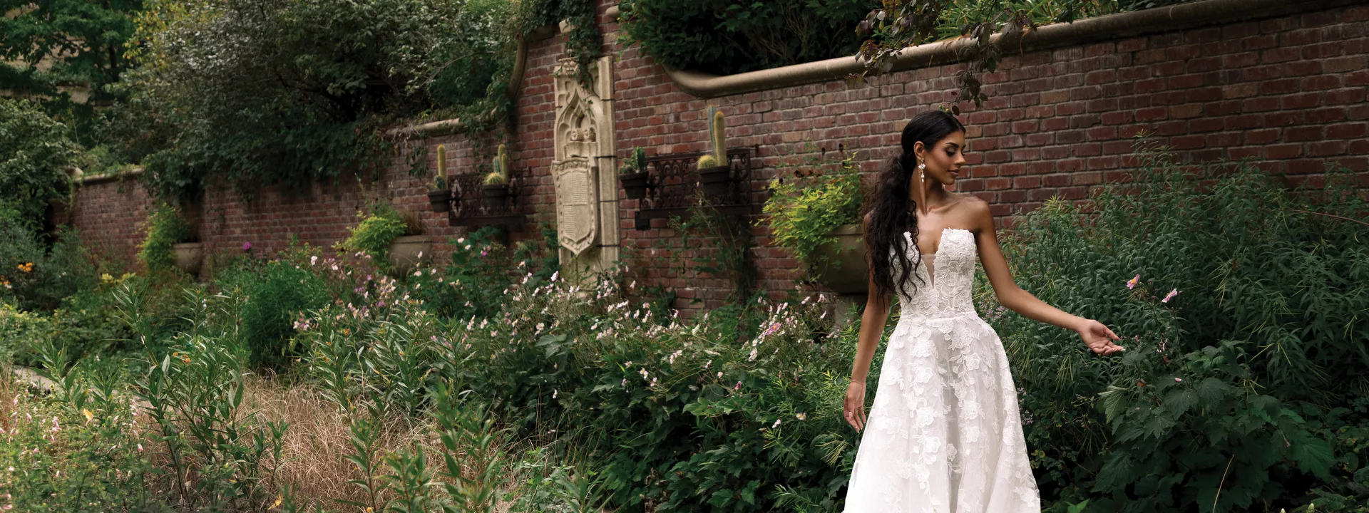 Model Kami Buchanan poses in a strapless lace gown against the verdant backdrop of the Lauritzen Gardens
