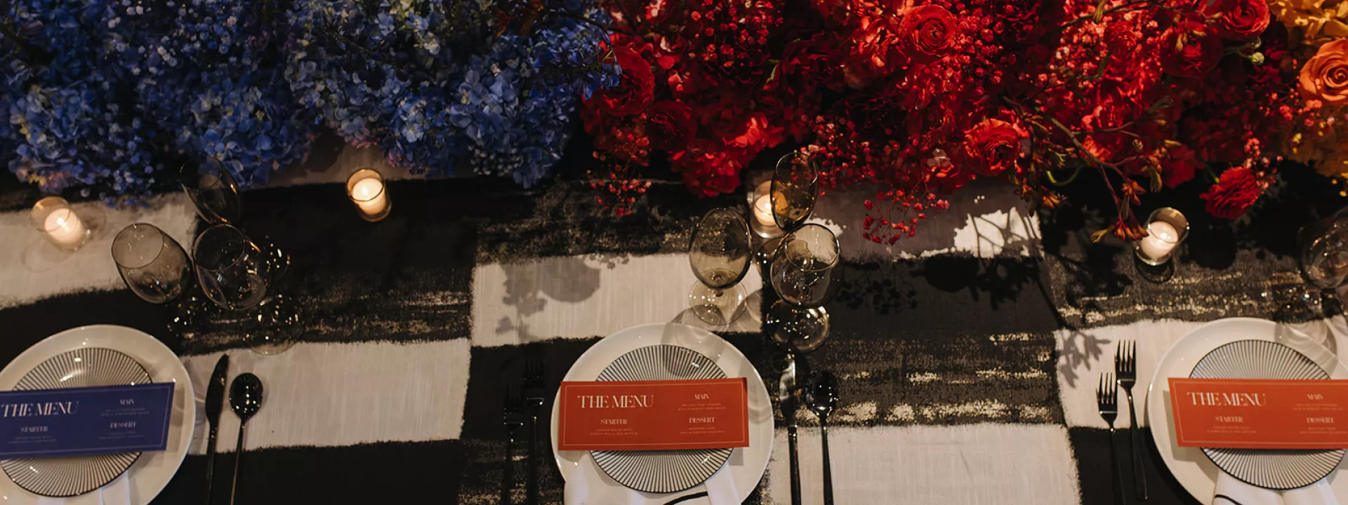 Maximalist tablescape featuring black and white checkered tablecloth and ombre rainbow florals