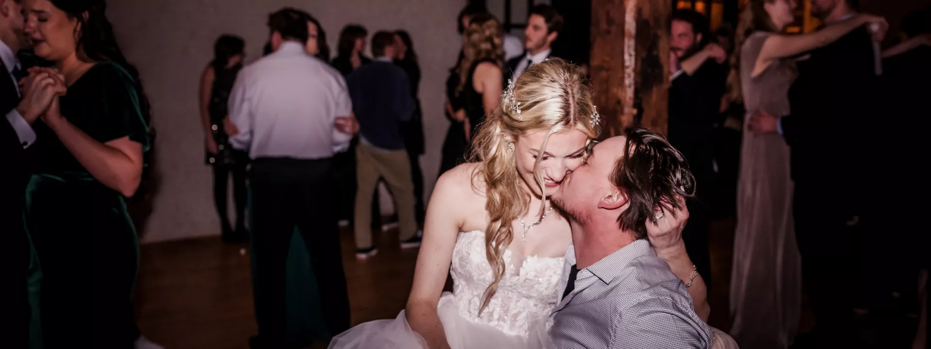 Elizabeth sits on Matthew's lap as they share a kiss on their rustic wedding day at The Lageret