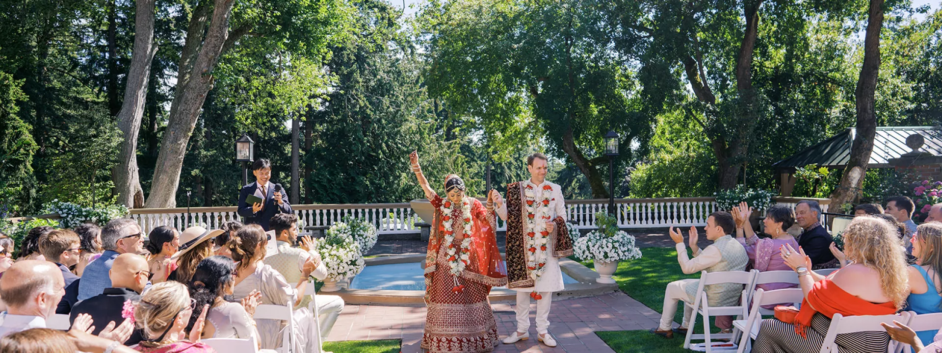 Bride and groom raise their hands in celebration while walking back down the aisle in outdoor ceremony at Lairmont Manor