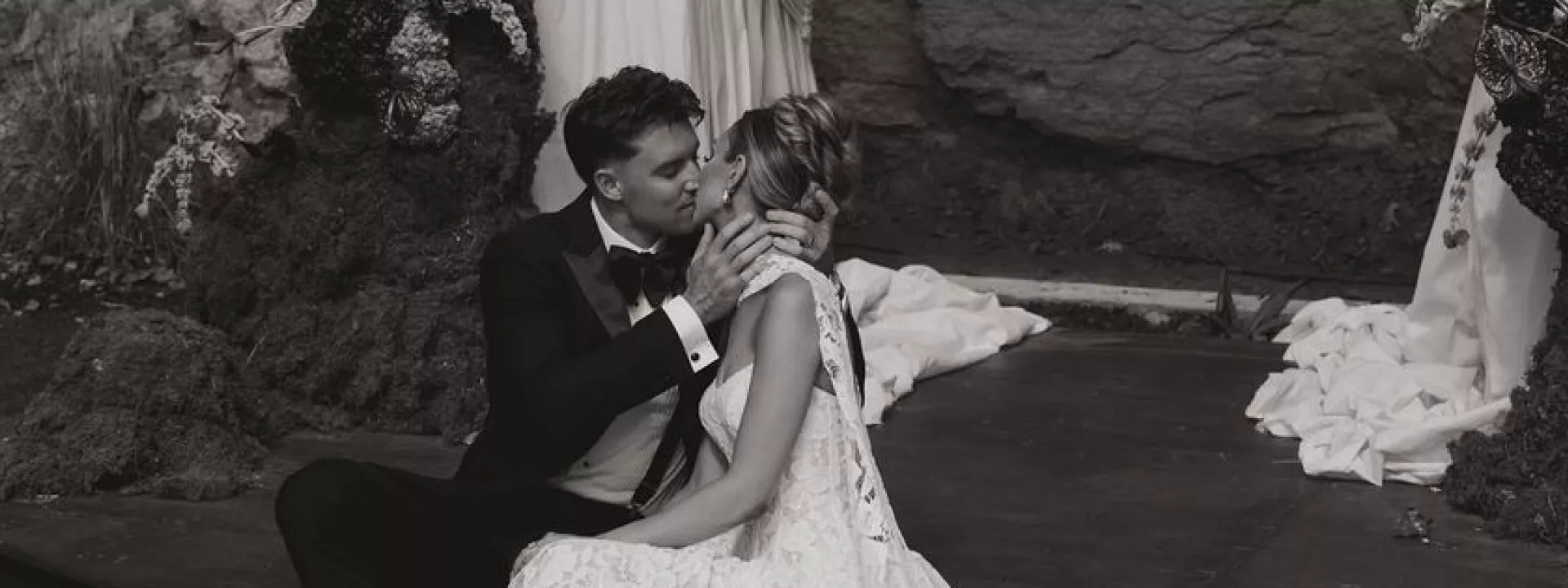 Bride and groom share a kiss sitting at their outdoor altar at Woods & Co.