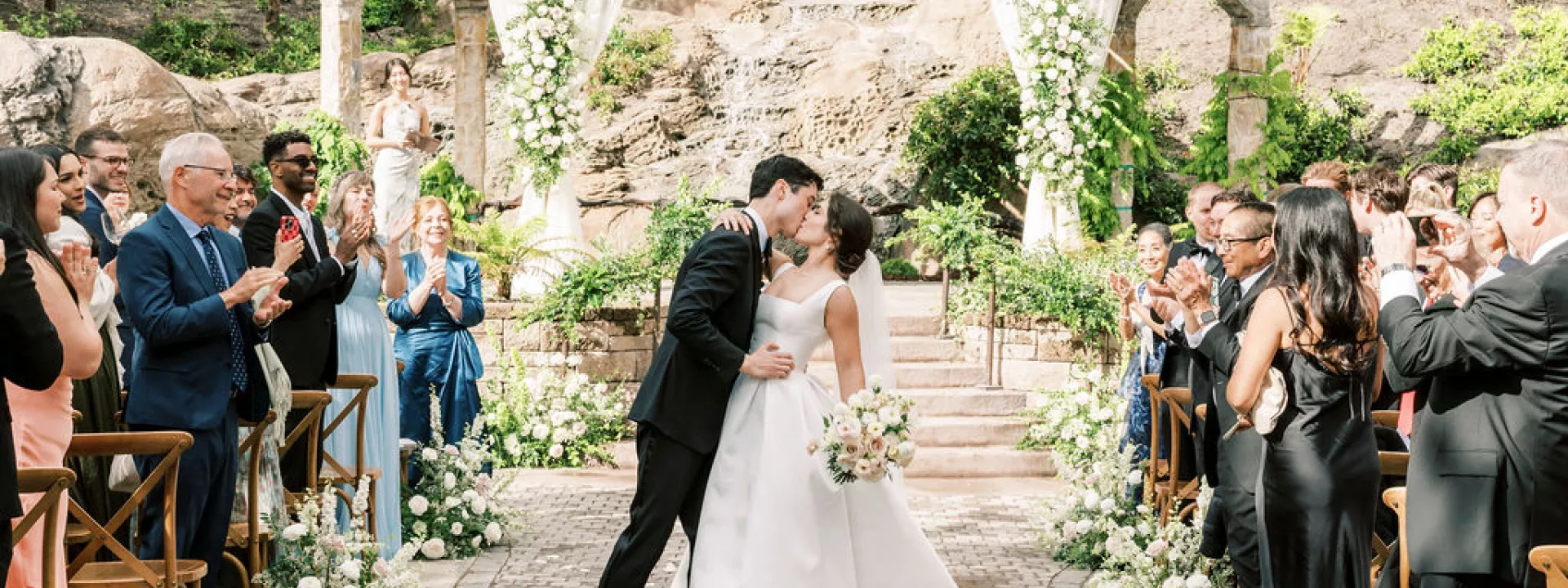 Bride and groom share a kiss at the end of the aisle after exchanging vows in outdoor ceremony at Villa Loriana