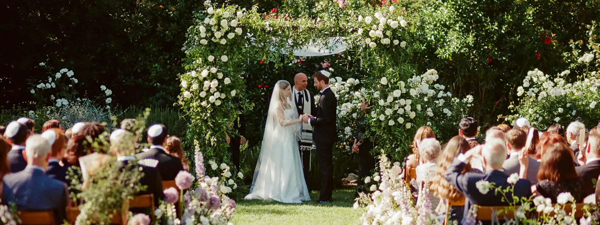 Bride and groom stand under chuppah during enchanted garden wedding ceremony at The Lodge at Malibou Lake