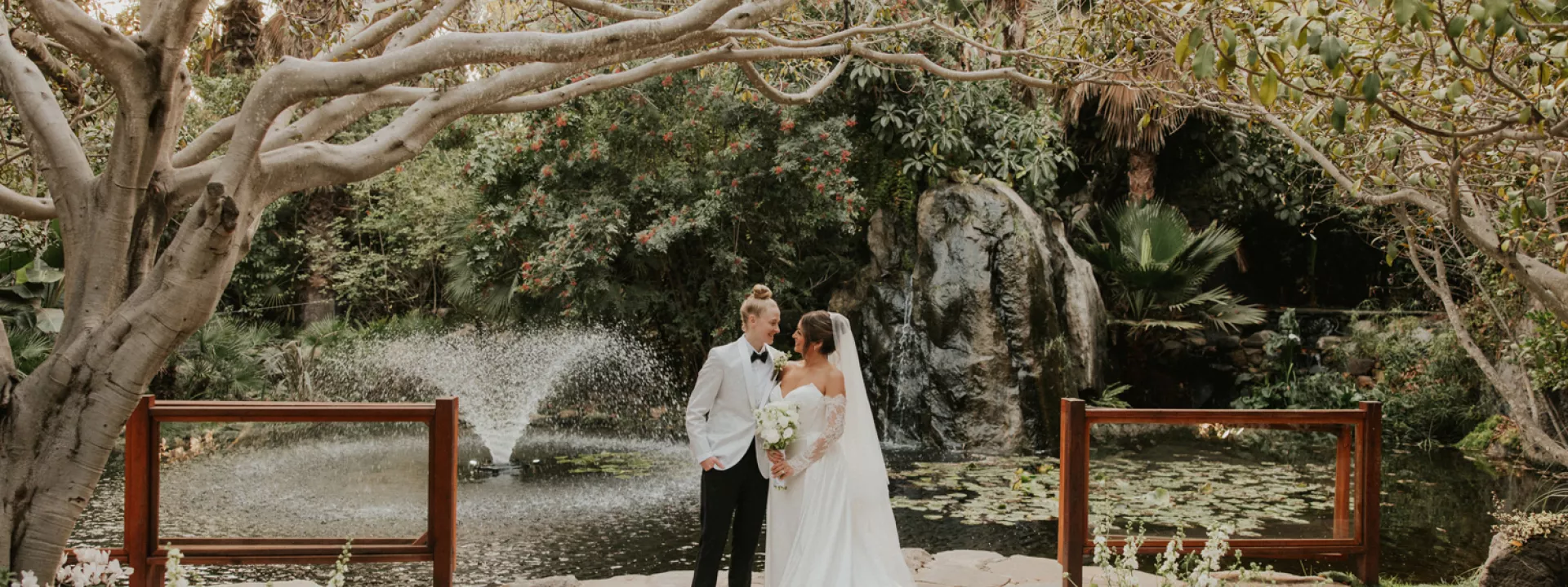 Taylor and Summer embrace on the grounds of Botanica on their wedding day