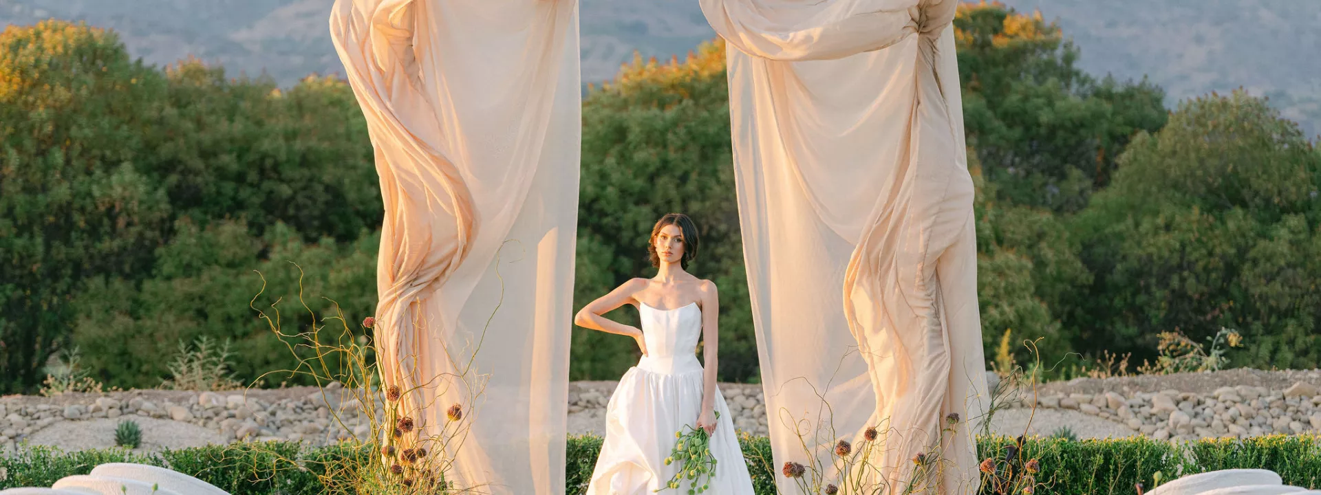 Model poses under architectural and organic altar against mountainous landscape at Topa Vista