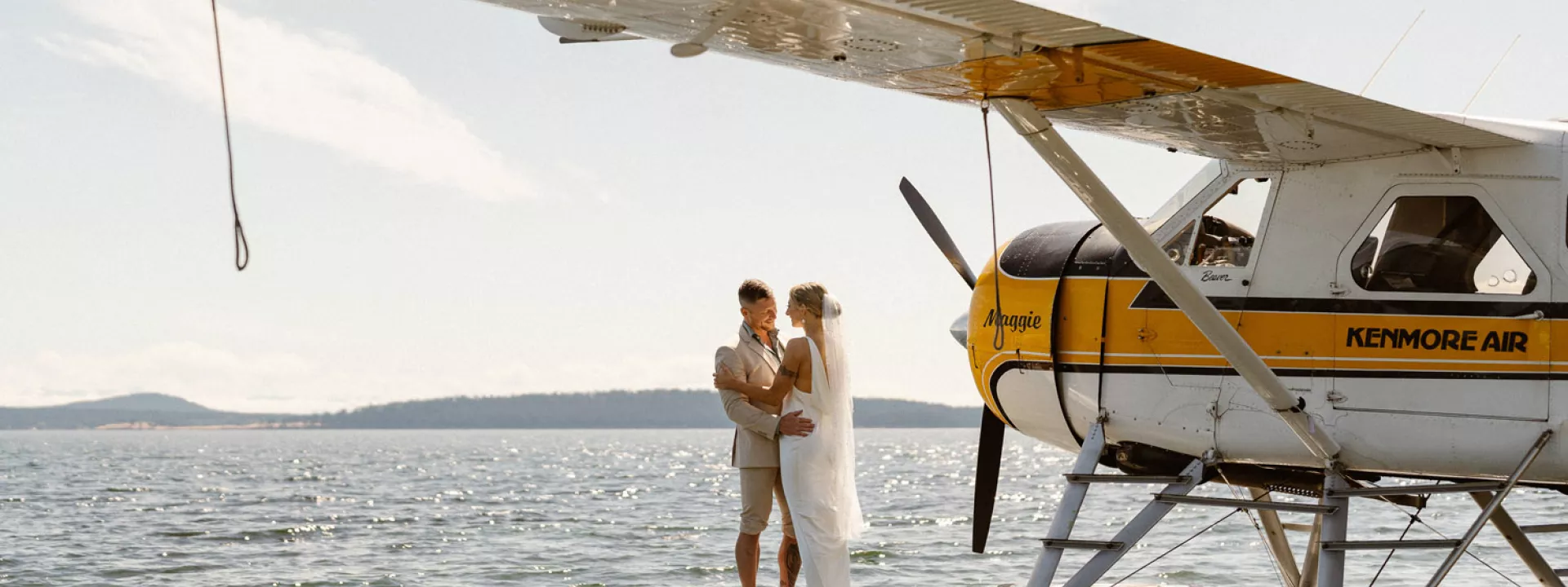 Bride and groom share a kiss next to seaplane off Orcas Island for elopement