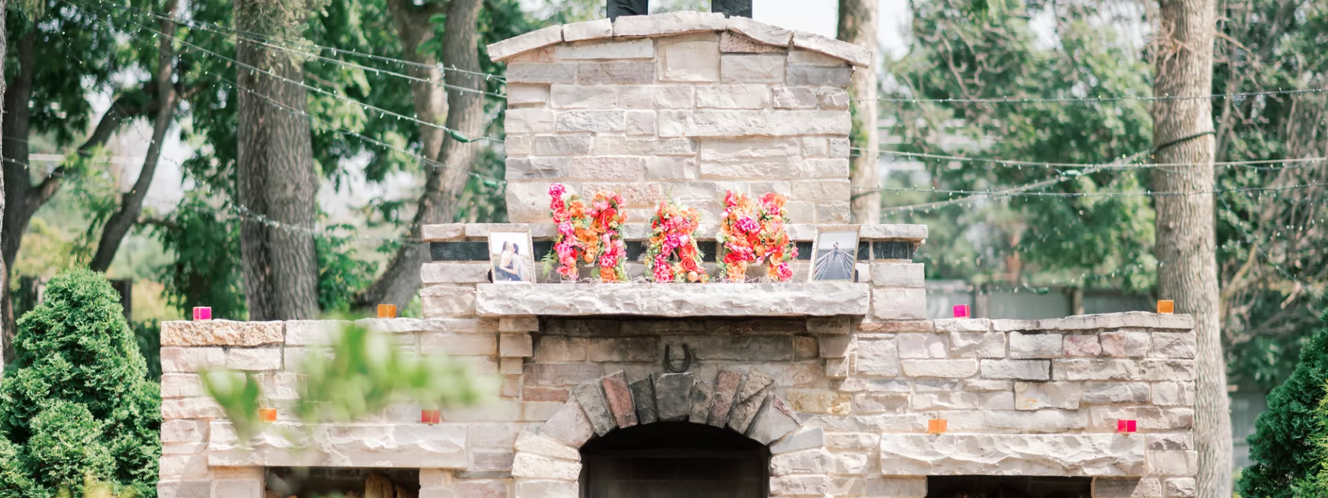 "M + M" Spelled out with floral arrangements atop an outdoor fireplace at The Gardens of Castle Rock