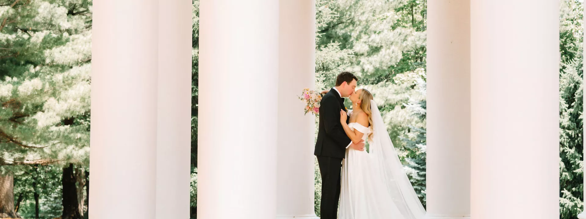 Bride and groom embrace in stone gazebo in wedding day at Arbor Day Farm