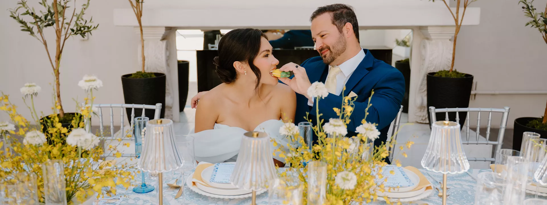 Groom feeds bride a lemon shaped macaron at an Amalfi Coast inspired tablescape 