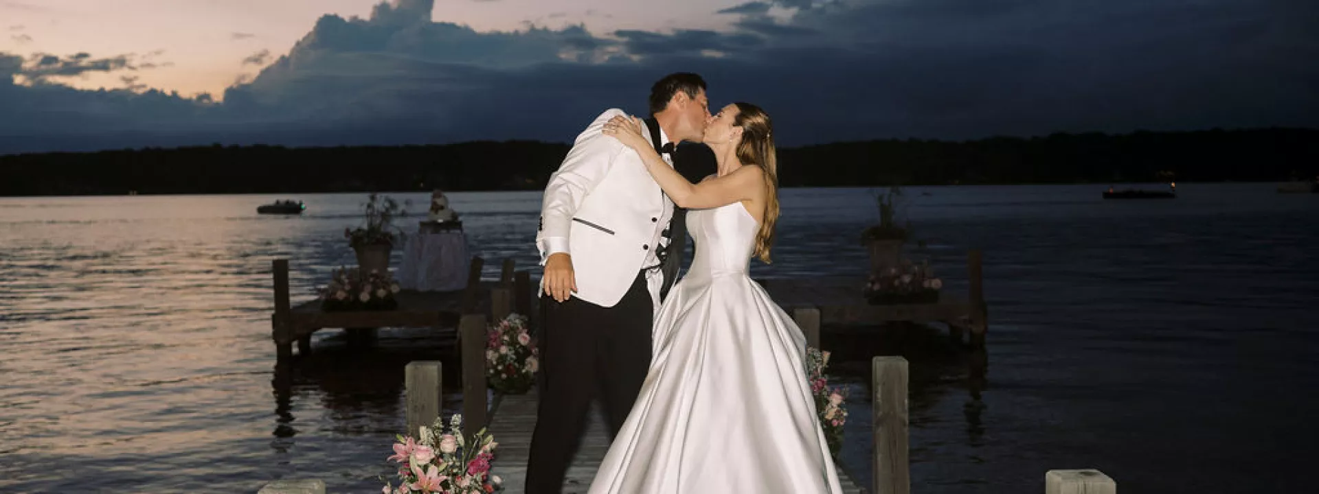 Bride and groom share a kiss against the sunset on Pewaukee Lake