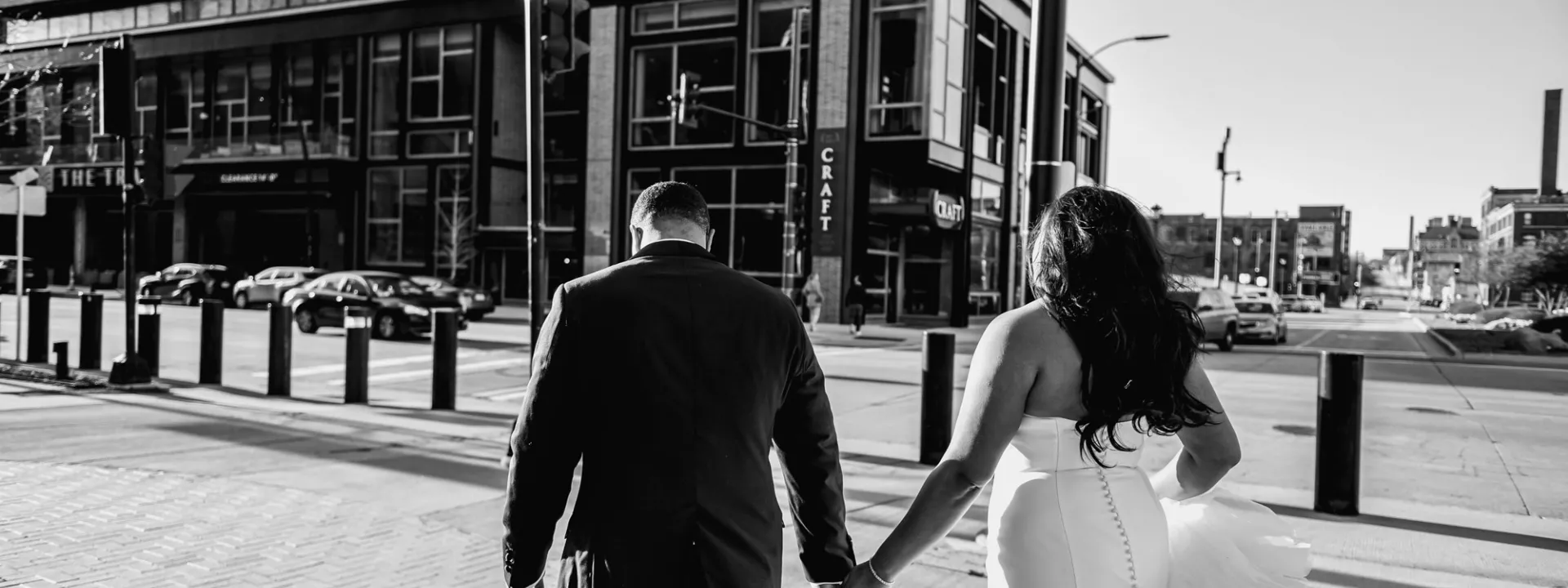 Bride and groom hold hands as they cross the street to the Trade Hotel