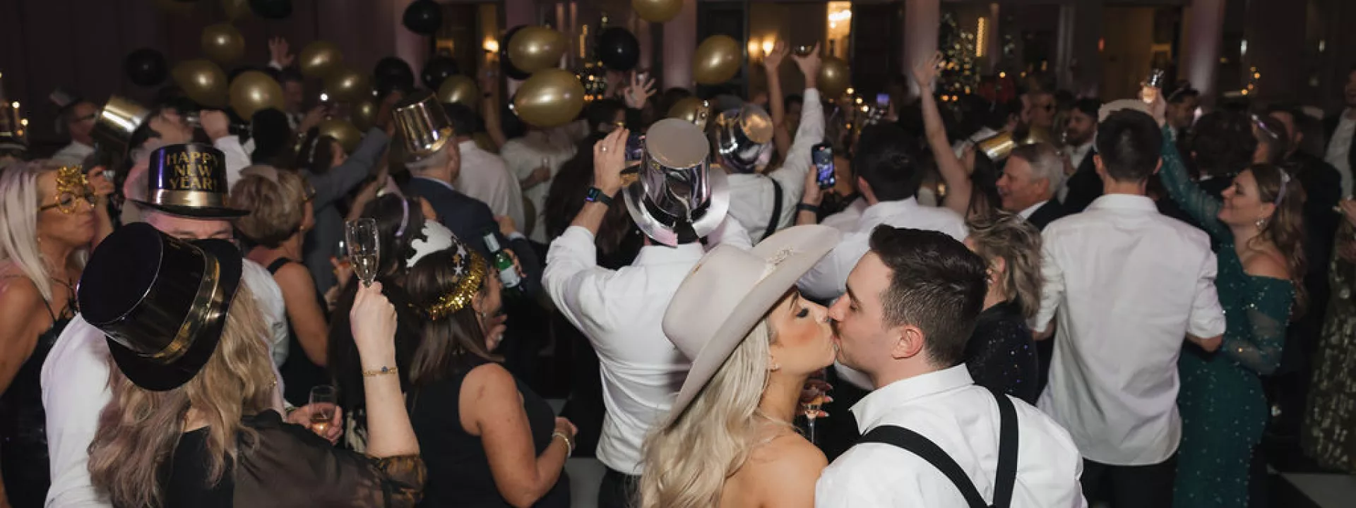 Bride and groom kiss on crowded dance floor during New Year's balloon drop at The Pfister
