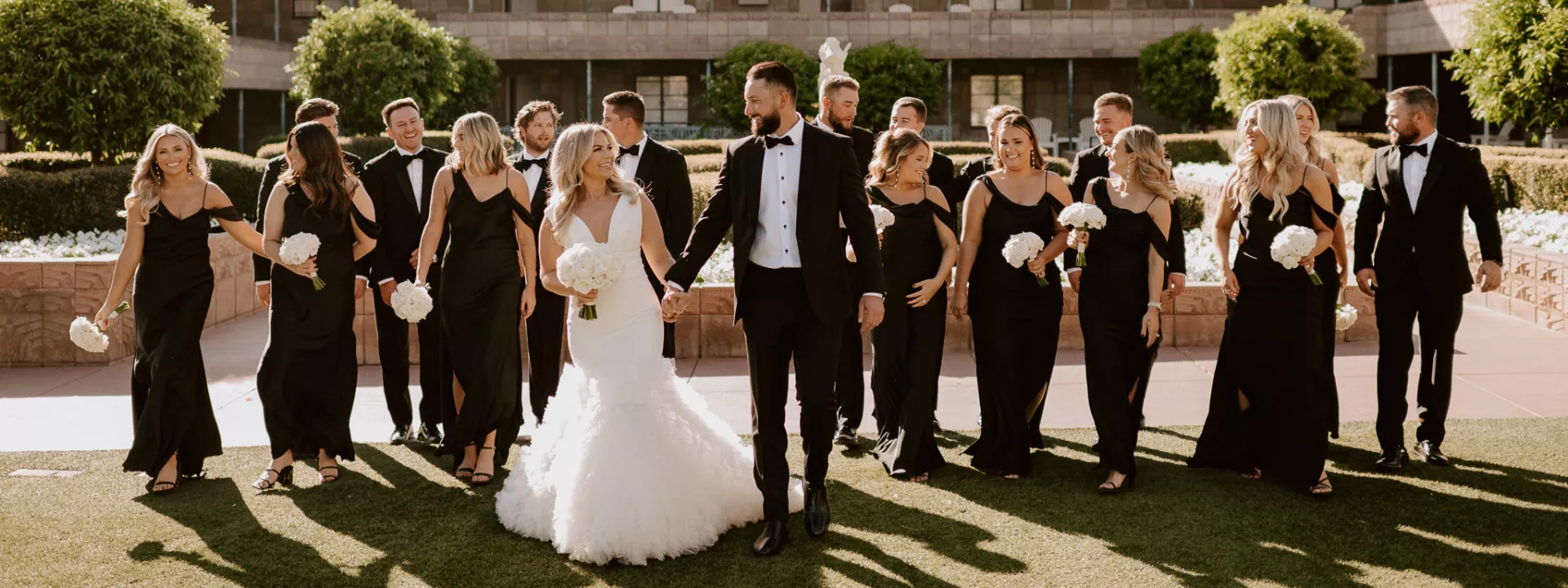 Bride and groom smile with their wedding party dressed in black