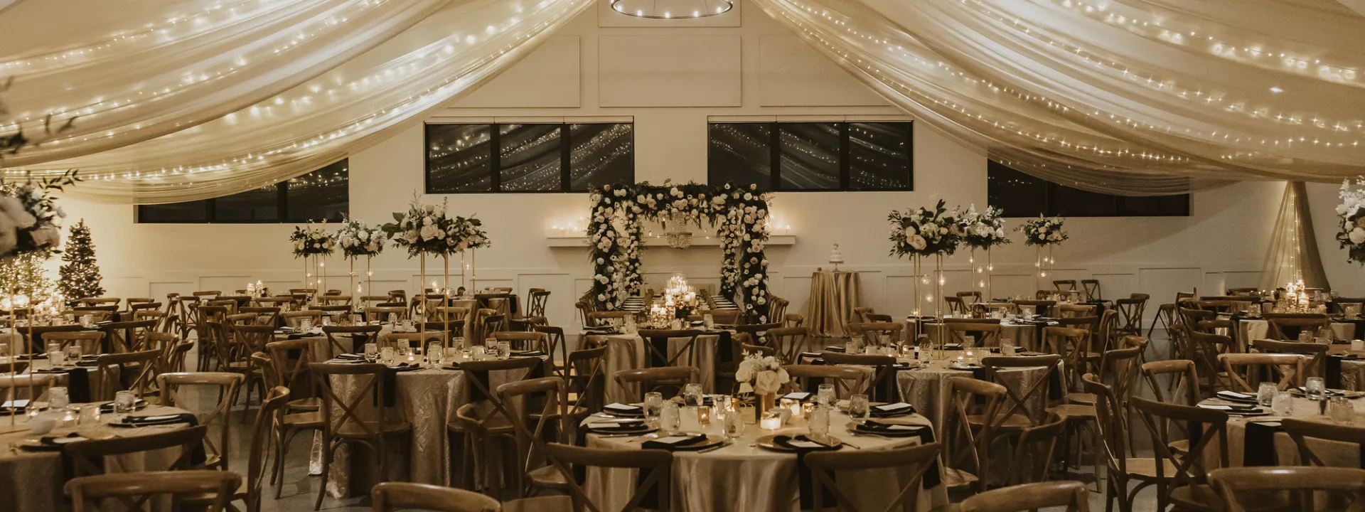 Classic and elegant reception design featuring draping and ivory florals in winter wedding at Woodhaven