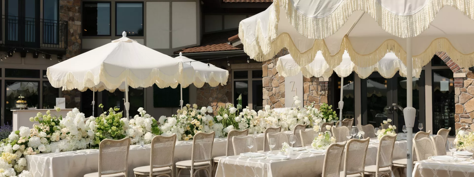 Long tablescapes shaded by soft yellow umbrellas, accented by lush florals in outdoor reception scene at Belle Âme Vineyard