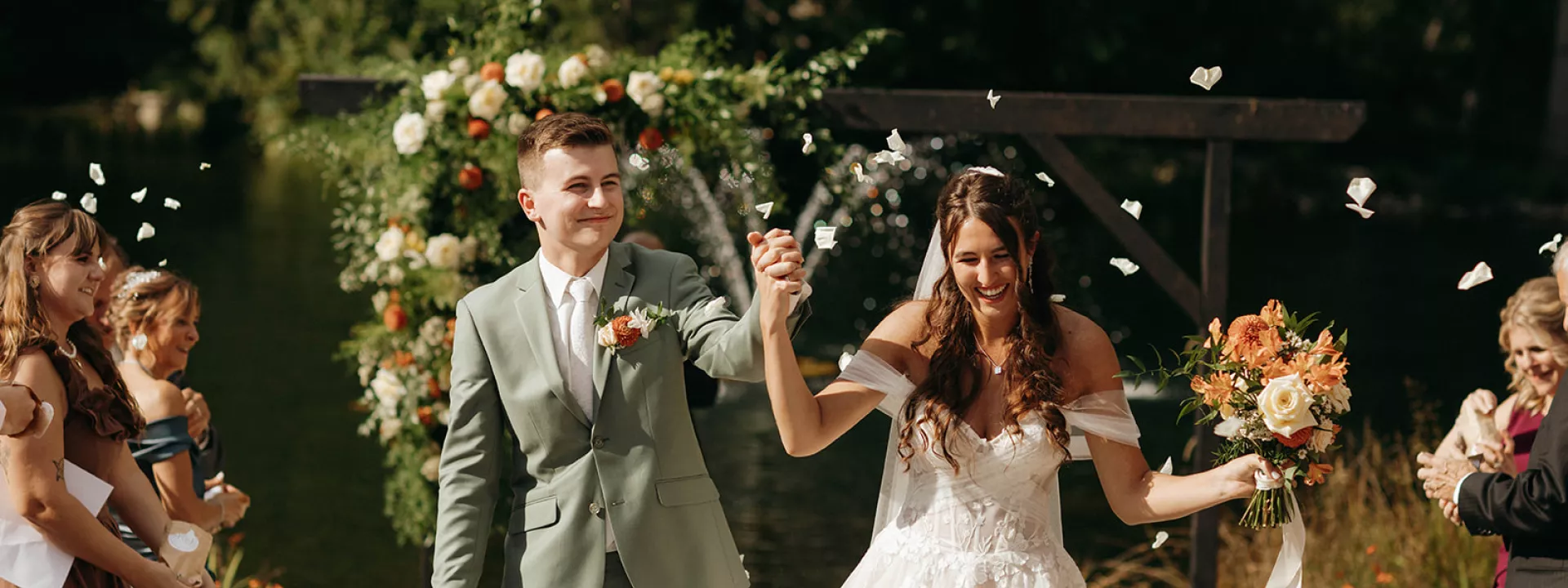 Bride and Groom hold hands and smile while walking back down the aisle
