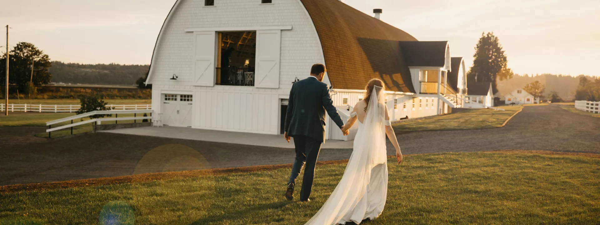 Katie and Connor walk hand in hand on the grounds of Fiddler's Bluff on their wedding day