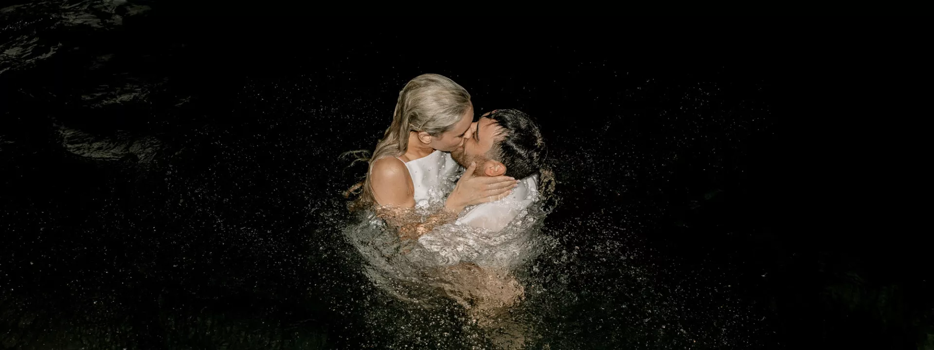 Bride and groom share a kiss in the waters of Lake Geneva in a light night dip in their wedding attire